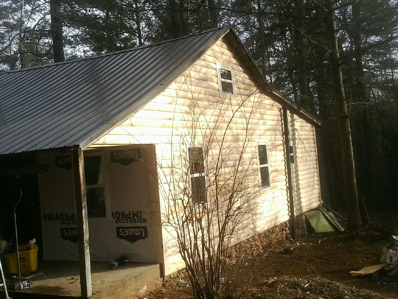 Log siding gable end under a dark metal roof edge in Morris