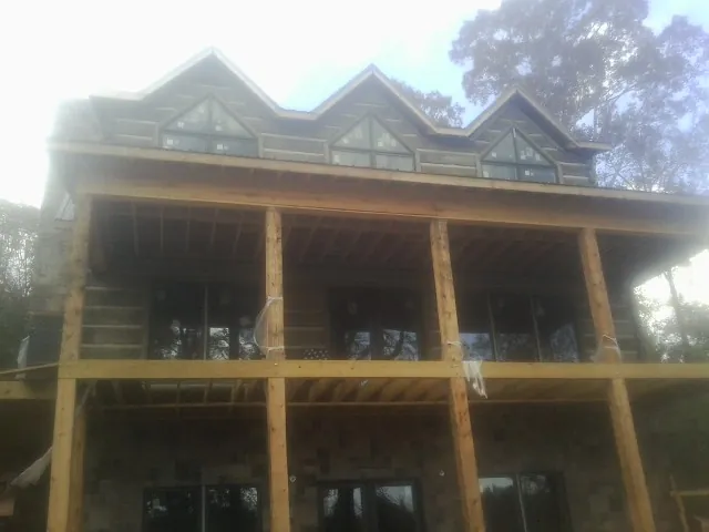 Dormers and porch framing on a large log home under construction — Roof Coating work by our crew in Morris