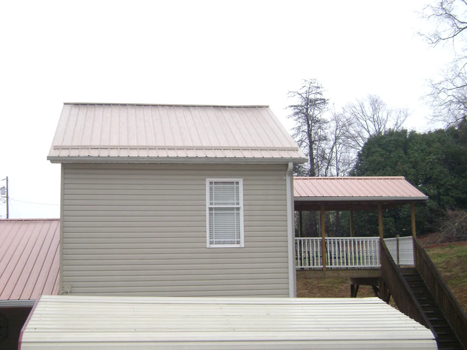 Tan metal roofs on a two story addition and attached porch, from a Roof Replacement job in Morris